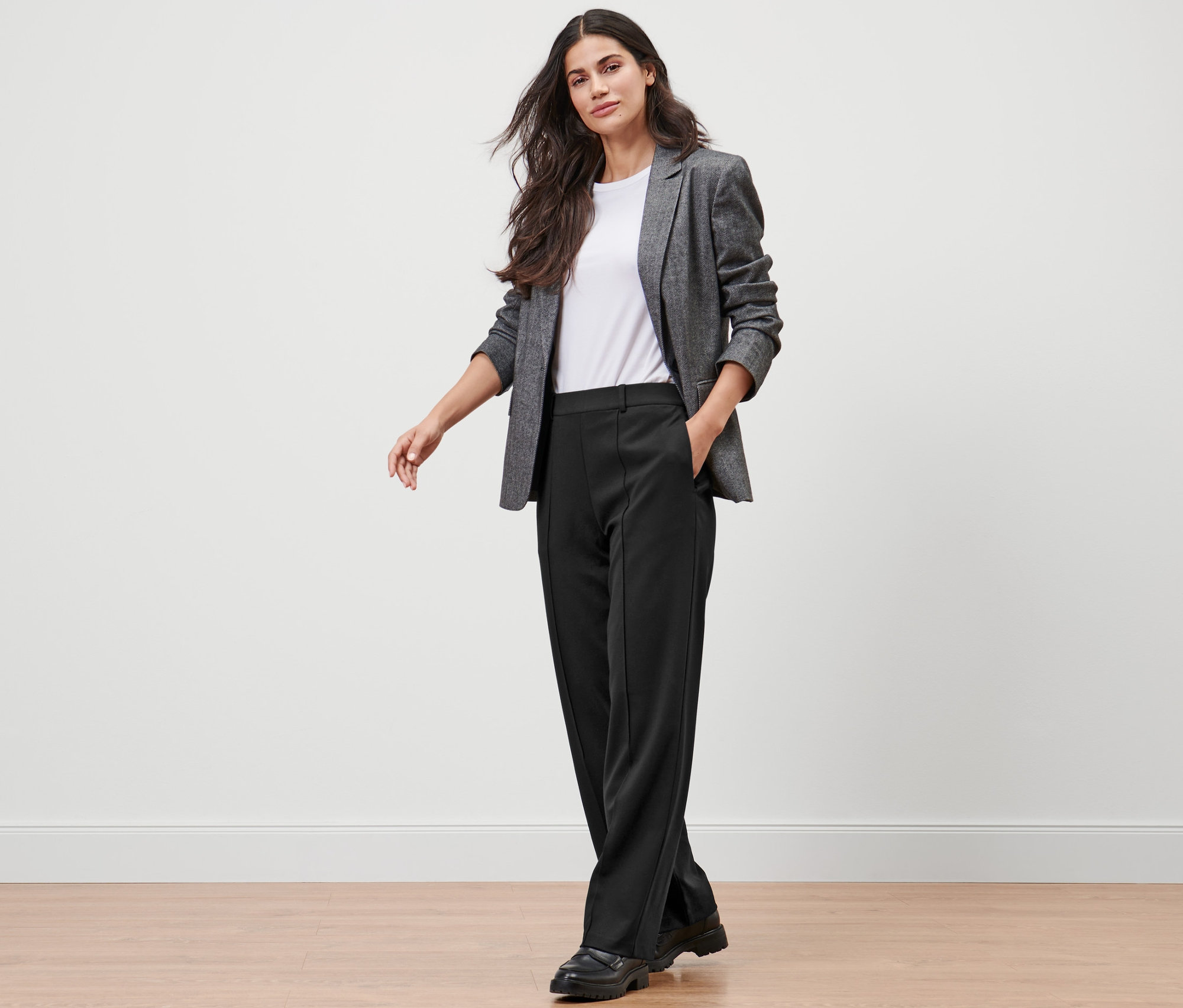 Frau trägt Sakko und schwarze Jerseyhose mit Biese.