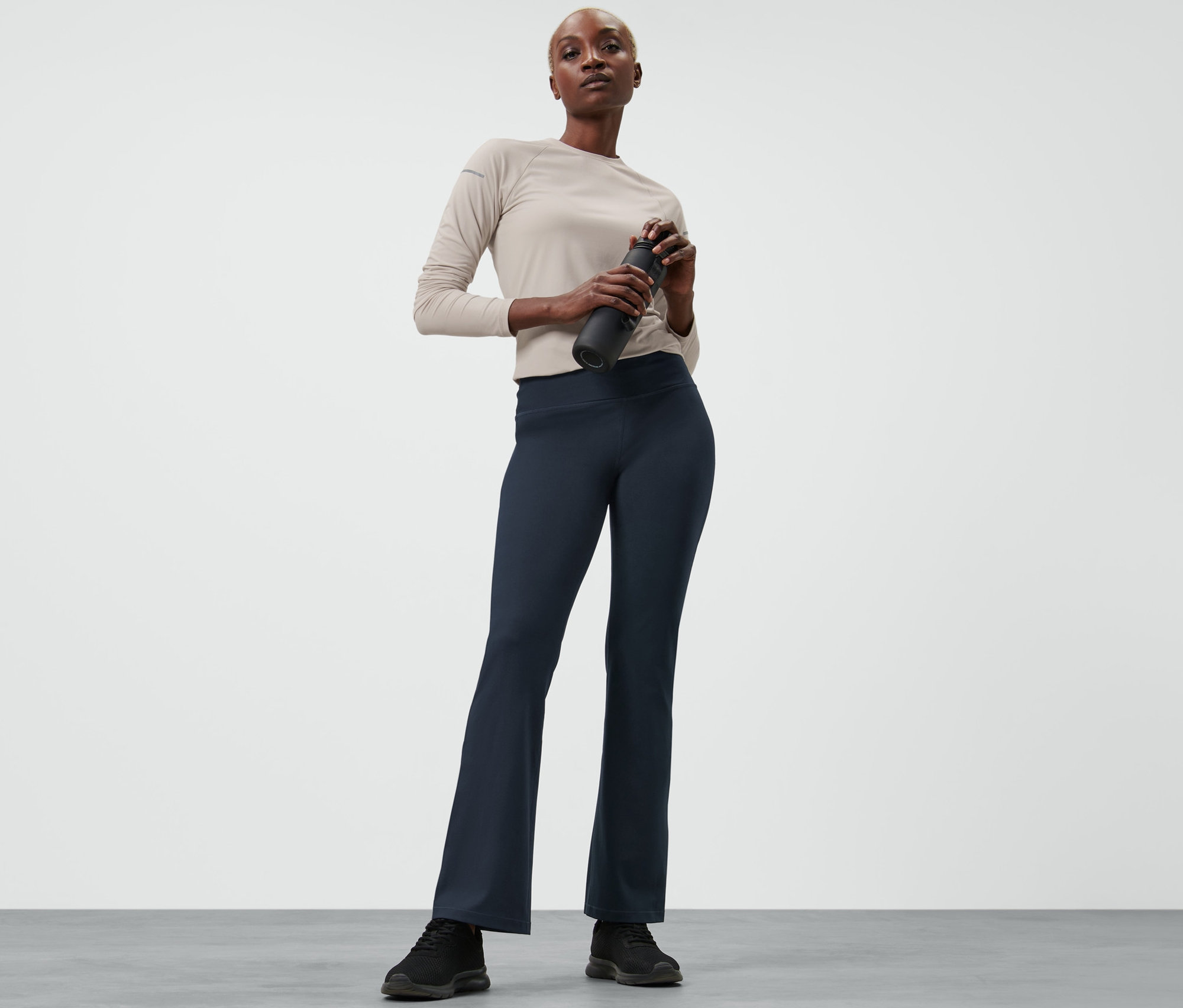 Frau hält Wasserflasche und trägt eine Bodyforming-Sporthose.