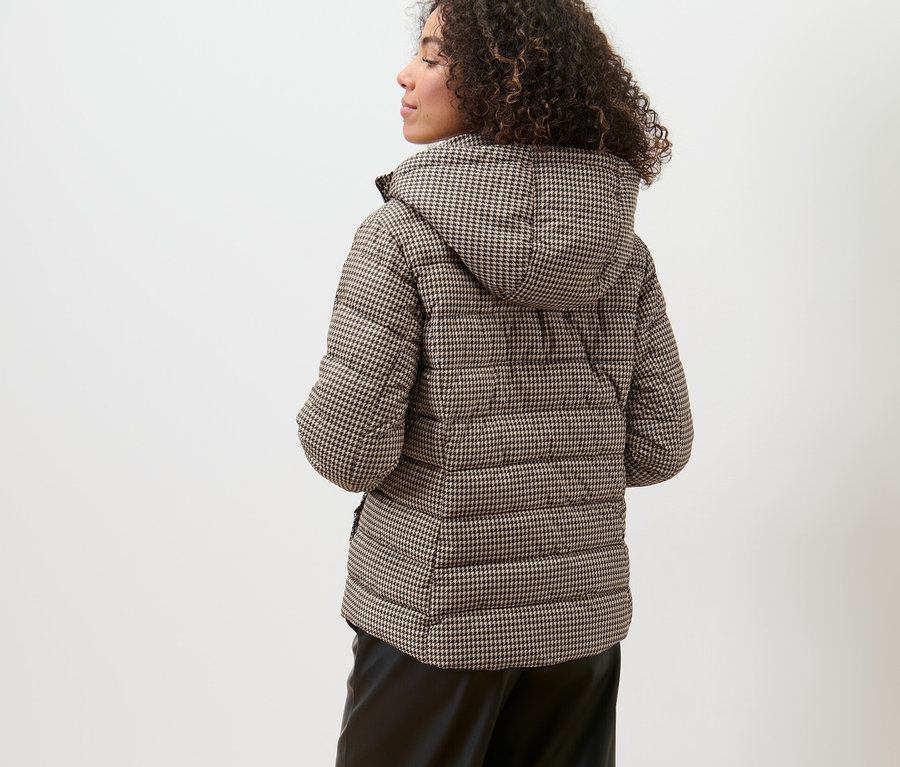 Frau trägt eine bedruckte Steppjacke mit Kapuze.