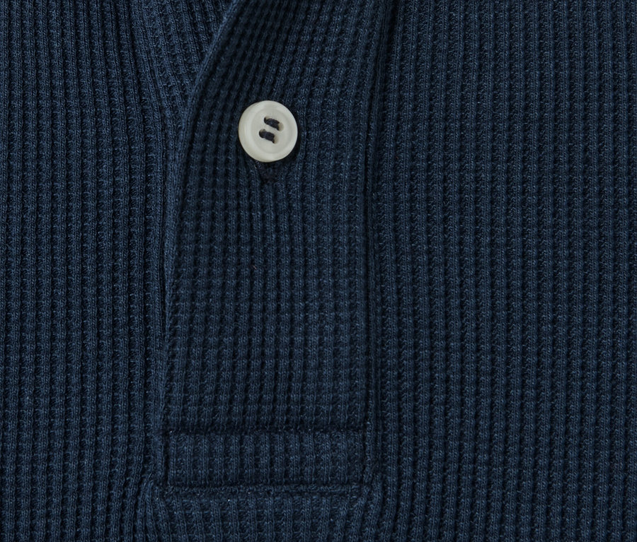 Detailaufnahme eines blauen Langarm-Poloshirts mit Knopf.