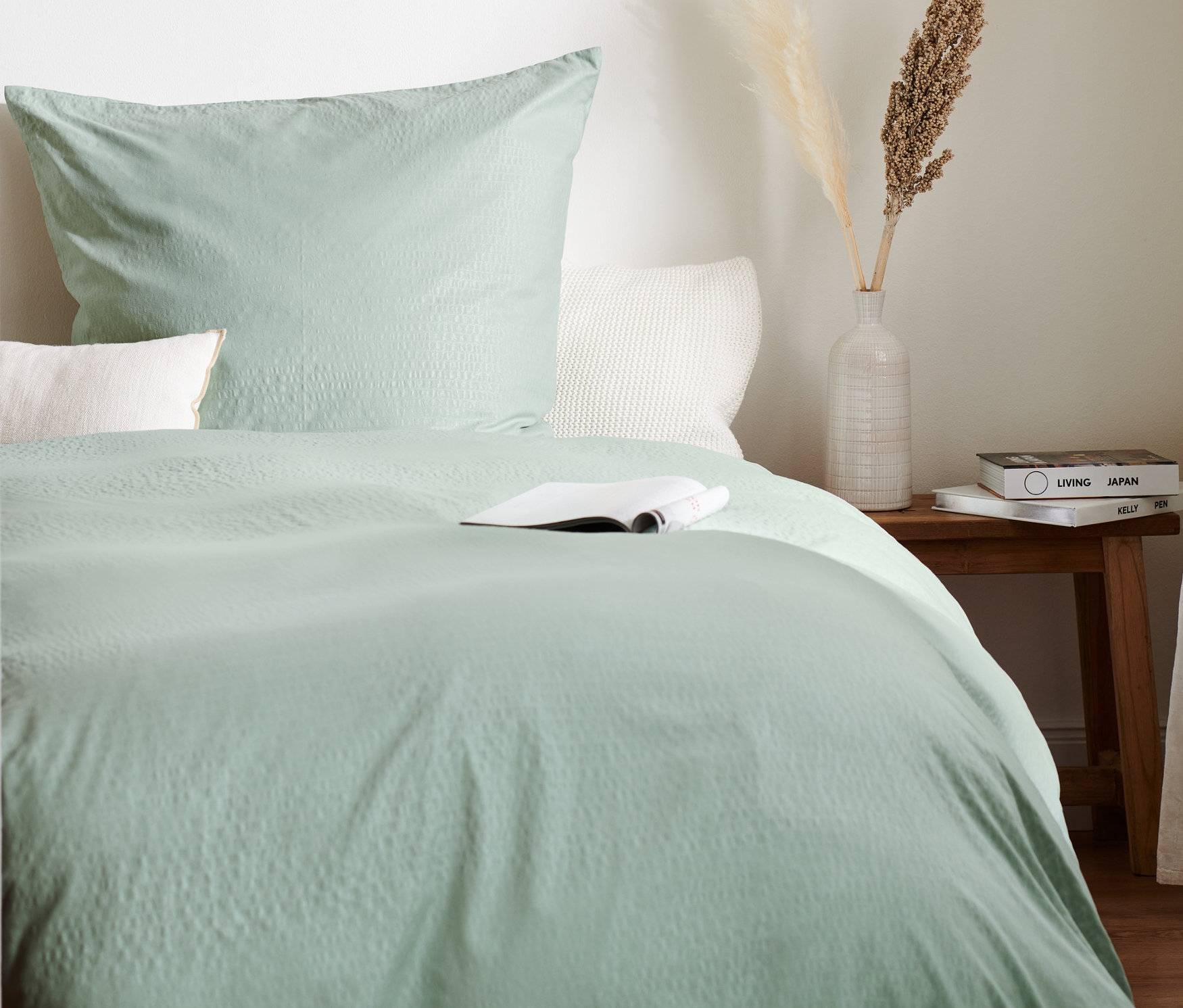 Grüne Seersucker-Bettwäsche Normalgröße, Übergröße und Doppelgröße auf einem Bett mit einem Buch.