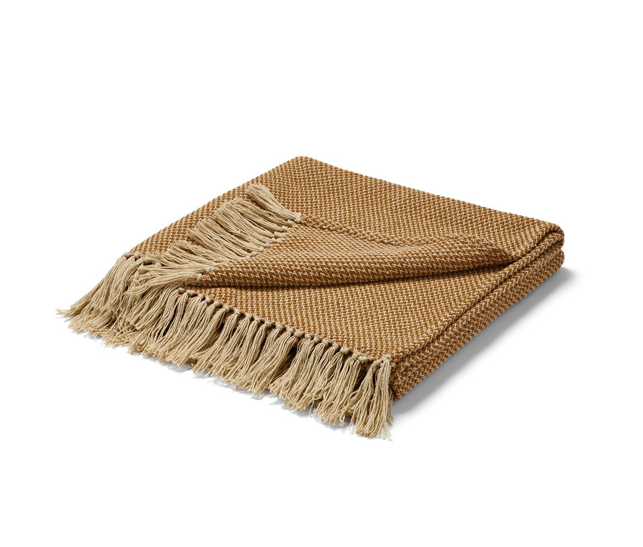 Eine braune Wohndecke mit Fransen liegt gefaltet auf einem weißen Hintergrund.