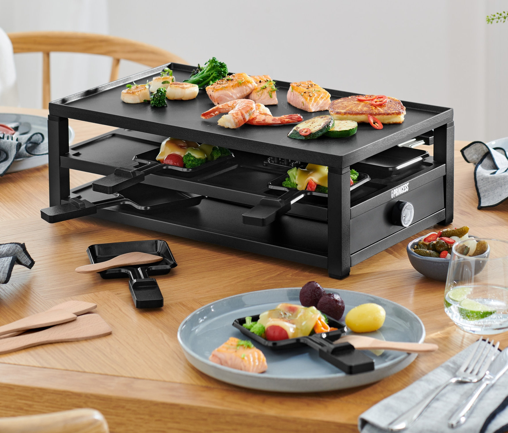 Raclette für 8 Personen auf einem Tisch mit Essen auf Tellern.