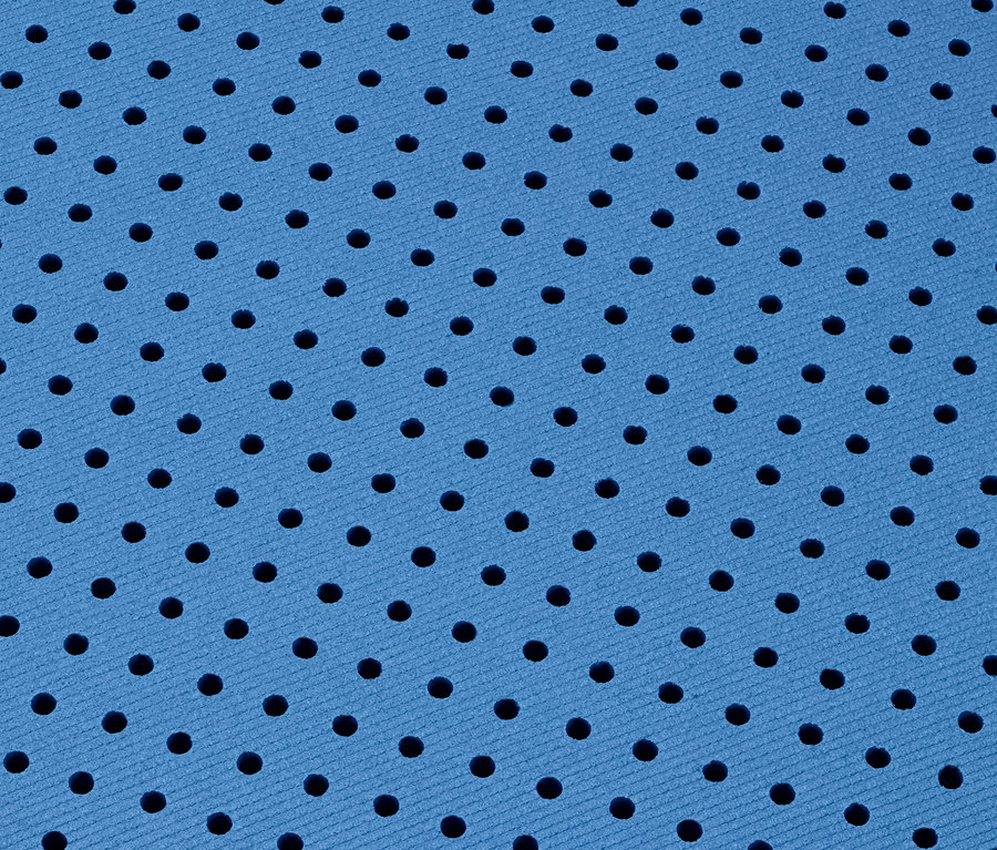 Nahaufnahme einer blauen Yoga-und-Fitnessmatte mit einem regelmäßigen Muster aus kleinen schwarzen Löchern.