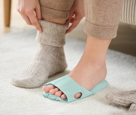 Eine Person trägt Entspannungssohlen, während sie eine Socke hochzieht.