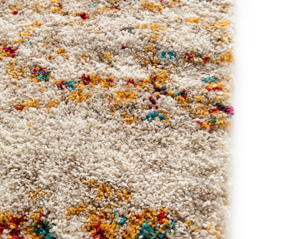 Detailansicht eines beigen Teppichs »Himalaya« mit Farbflecken.