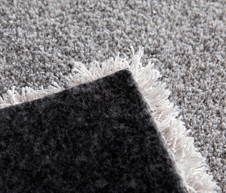 Detailansicht eines hellgrauen Teppichs »Mellow« mit Fransen.