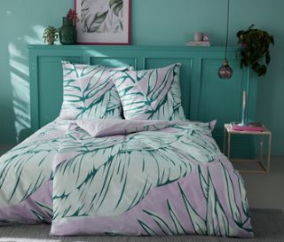 Bett mit Renforcé-Bettwäsche mit Blättermotiv.