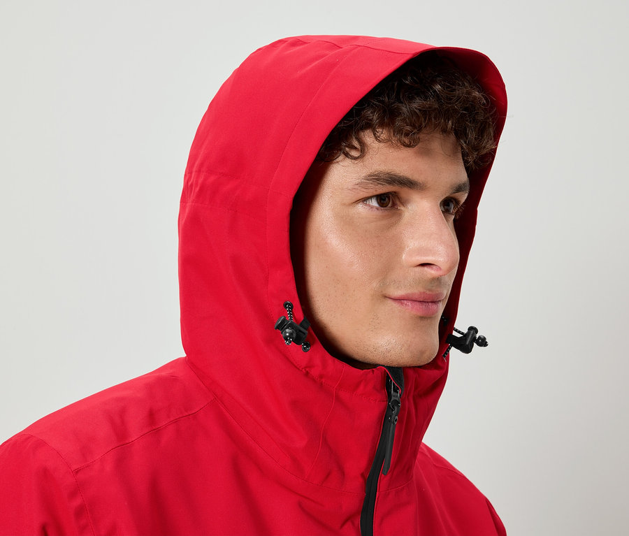 Mann mit lockigem Haar trägt eine rote Jacke mit Kapuze.