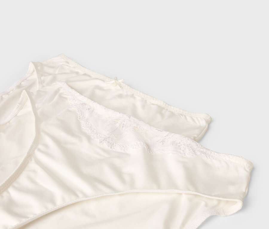 Zwei weiße Damenslips liegen übereinander.