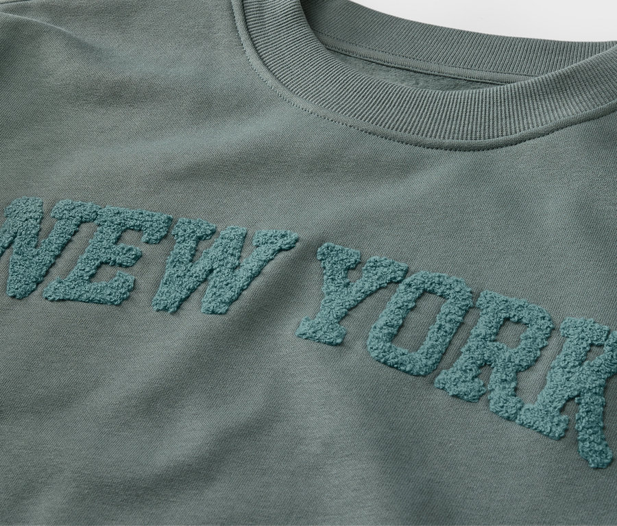 Detailansicht eines Kinder-Sweatshirts mit Frottee-Schriftzug NEW YORK.