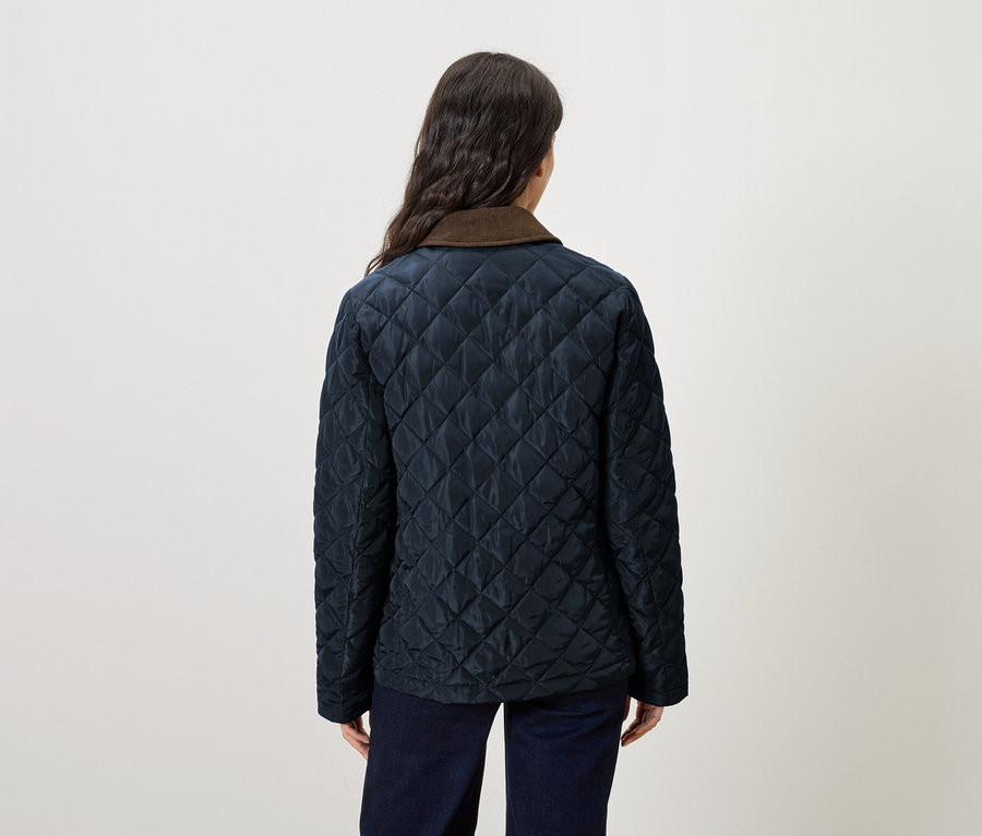 Frau trägt eine marineblaue Steppjacke mit braunem Kragen.