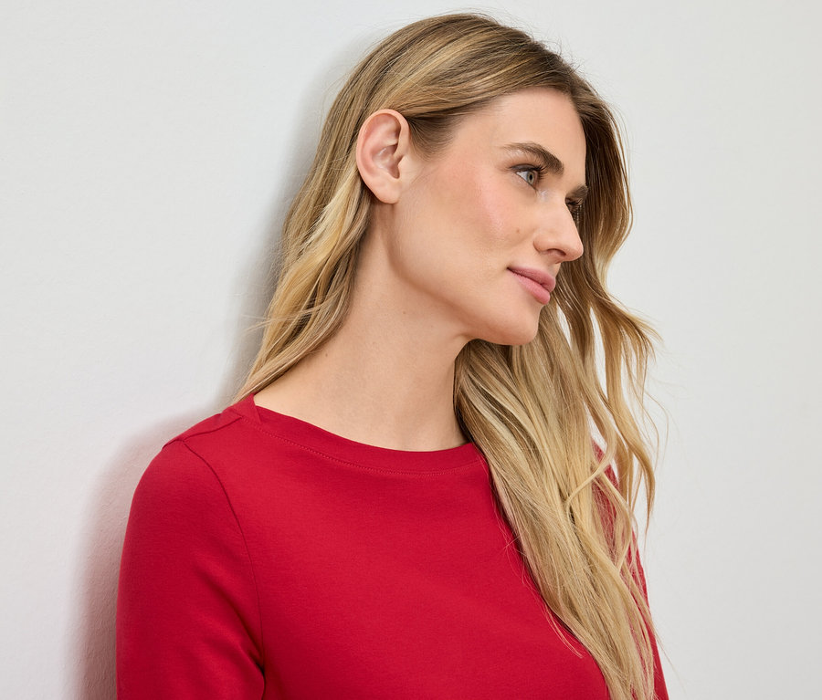 Profil einer blonden Frau in einem roten T-Shirt.