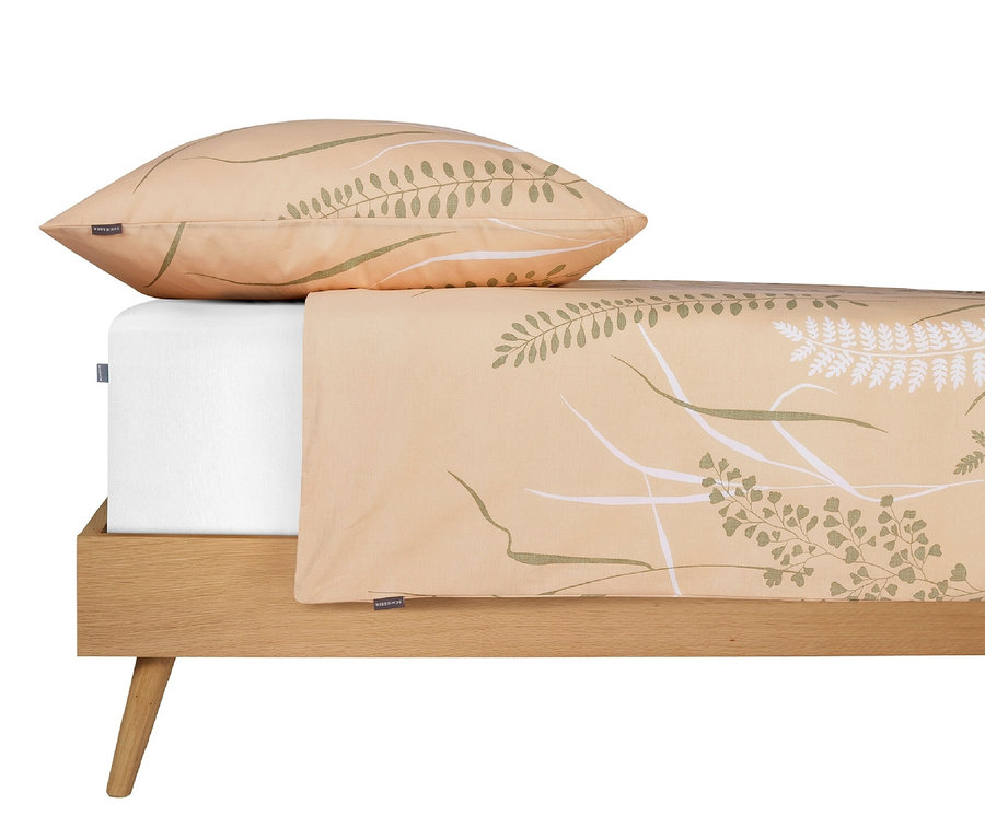 Ein sandfarbenes Bettwäsche-Set mit Botanikprint liegt auf einem Bett.