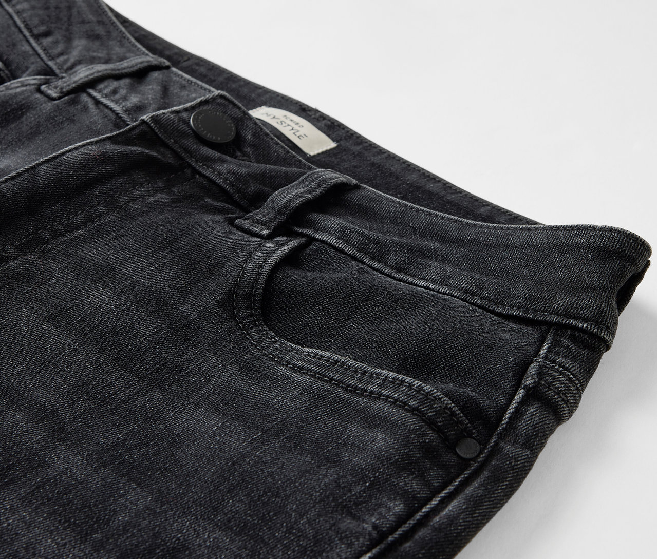 Detailaufnahme einer schwarzen Jeans mit Knopfverschluss und Vordertasche.