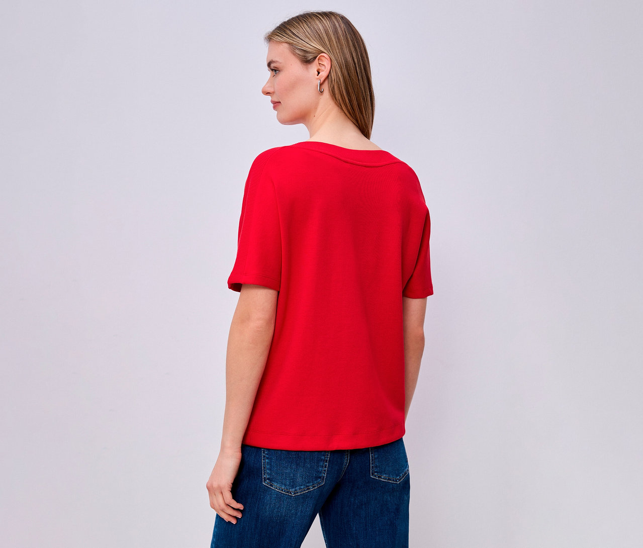 Frau von hinten in rotem Street One Kurzarmshirt und Jeans.