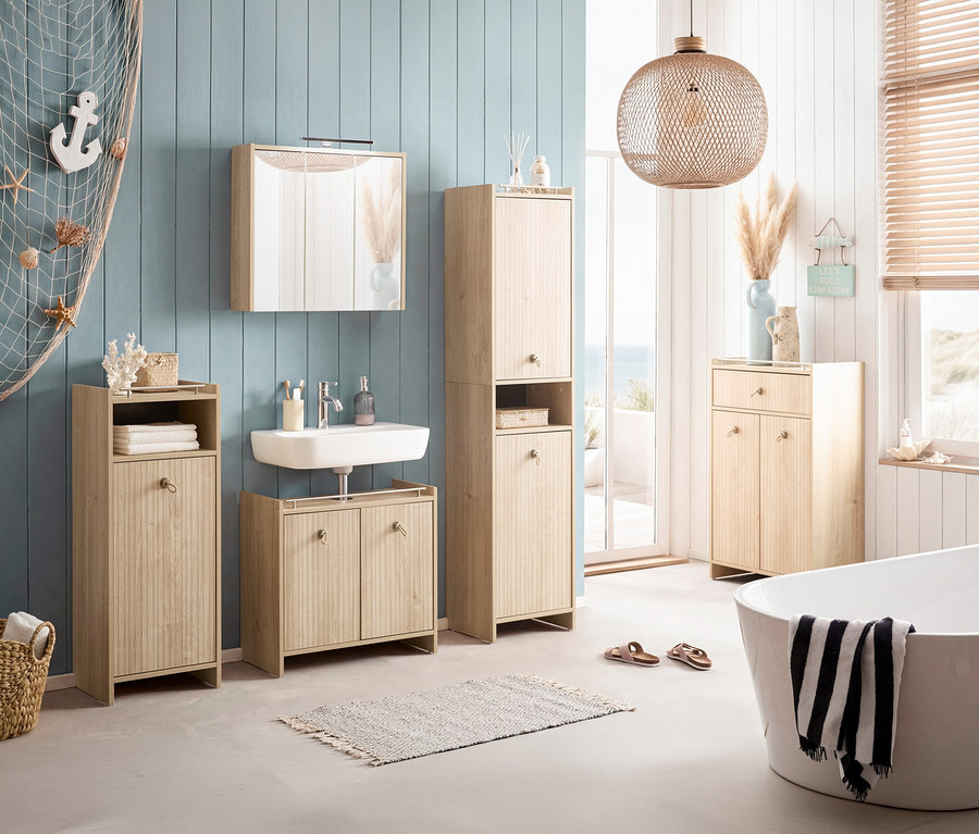 Badezimmer mit Waschtisch, Spiegelschrank und Hochschrank in Holzoptik. Badewanne mit Handtuch und Deko-Elementen. Fenster mit Meerblick.