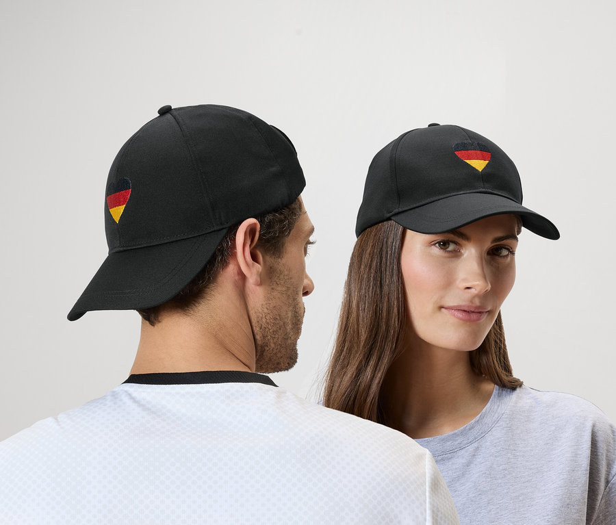 Mann und Frau tragen schwarze Kappen mit Deutschlandflagge-Herz.