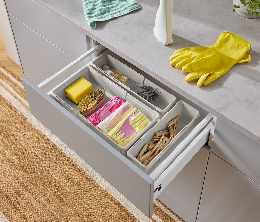 Geöffnete Schublade mit Spülutensilien: Schwamm, Bürste, Spültücher mit Lama-Motiv, Flaschenbürste, Topfreiniger, Wäscheklammern und gelbe Handschuhe.