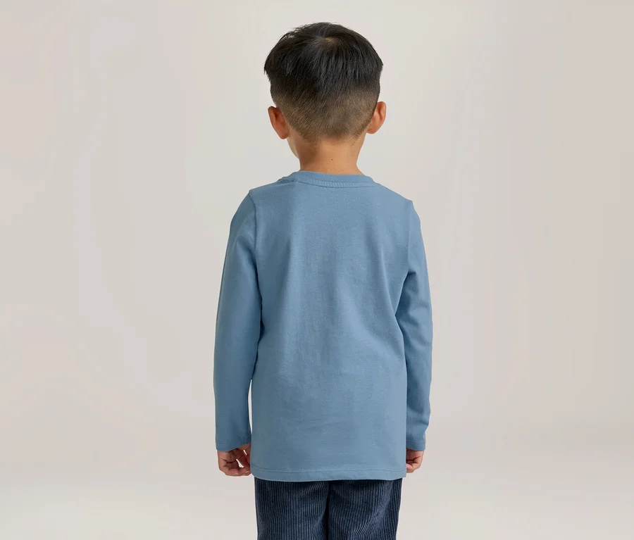 Junge von hinten, der ein blaues Langarmshirt und eine dunkelblaue Cordhose trägt.