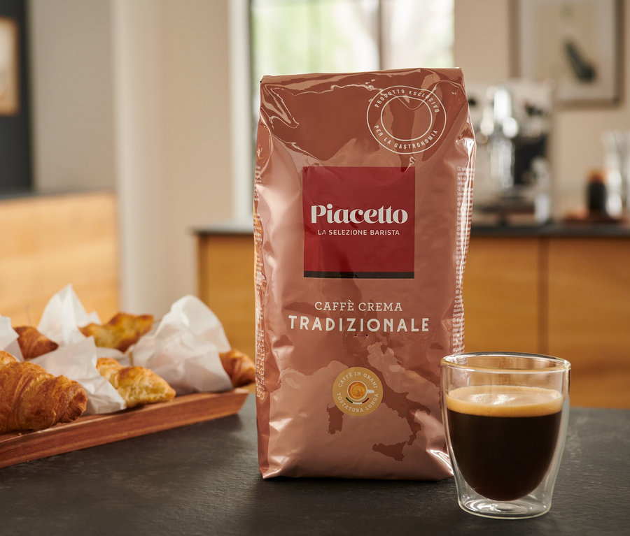 Eine Packung Piacetto Caffè Crema Tradizionale, Kaffee und Croissants auf einem Tisch.