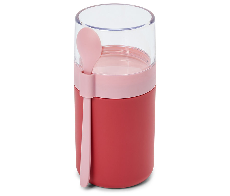 Ein roter Lebensmittelbehälter mit einem rosafarbenen Band und einem transparenten Deckel, an dessen Seite ein rosafarbener Löffel befestigt ist.