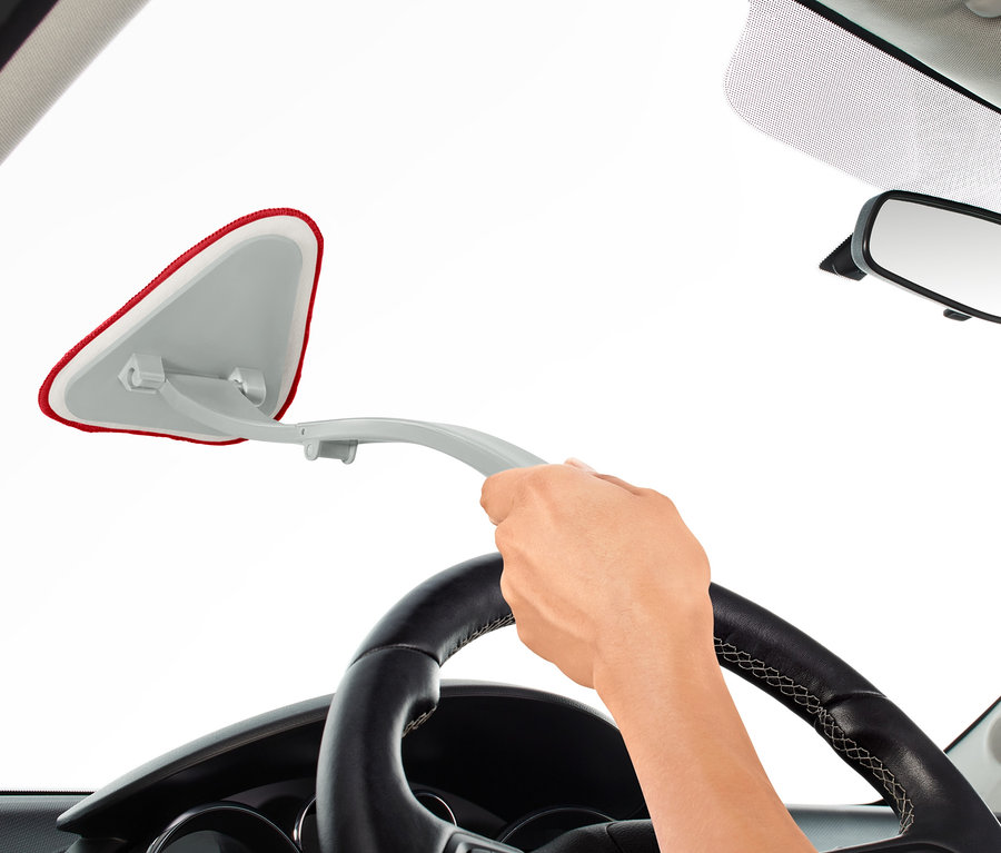 Eine Hand benutzt einen Auto-Windschutzscheiben-Reiniger von der Innenseite des Autos aus.