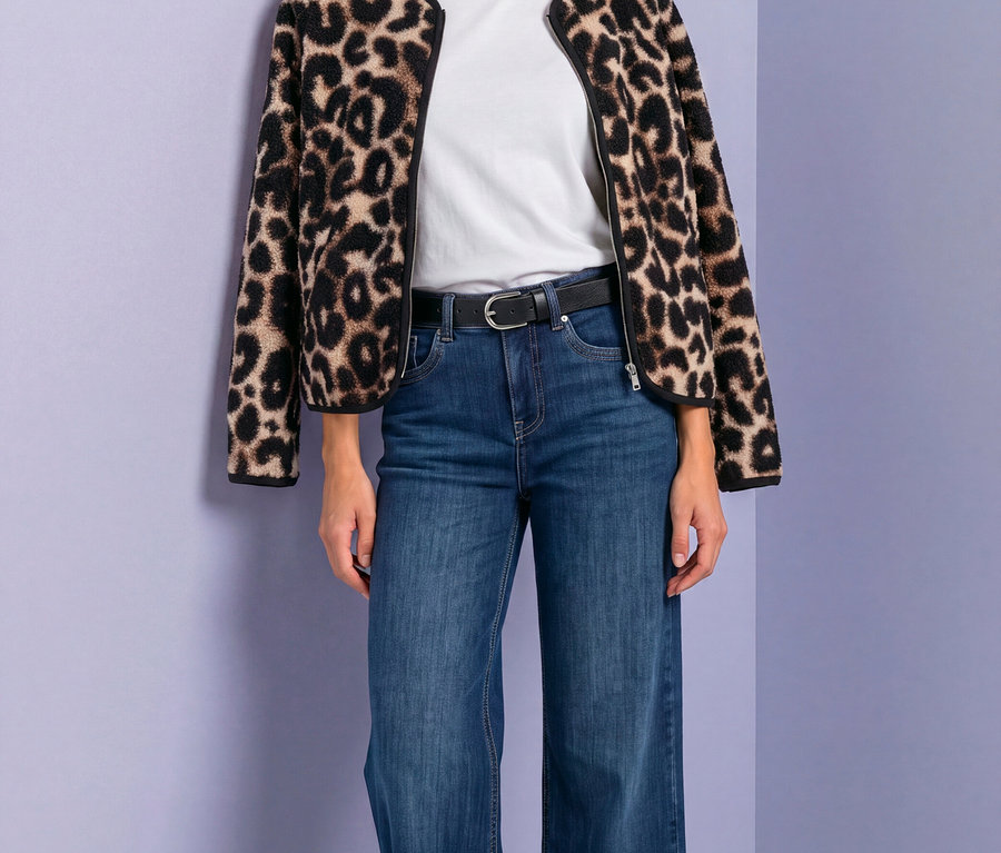 Frau in Street One Jacke mit Leopardenmuster, weißem T-Shirt, blauen Jeans und schwarzem Gürtel.