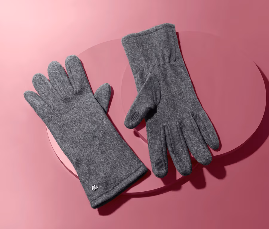 Zwei Fleecehandschuhe auf rosafarbenem Hintergrund.