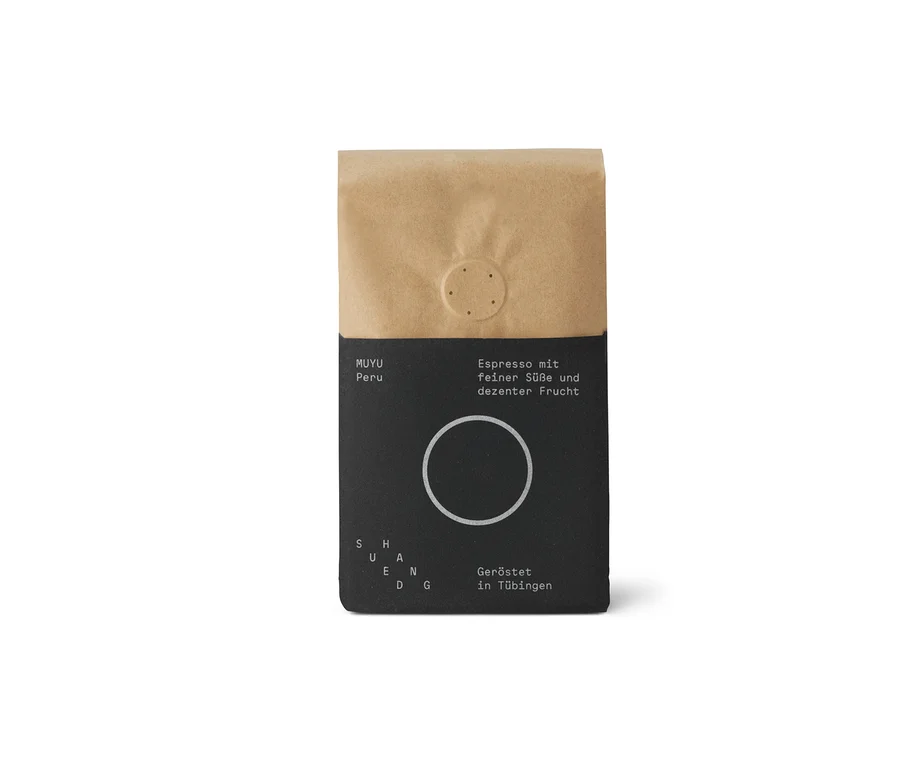 Eine aufrecht stehende Kaffeepackung SUEDHANG - MUYU Espresso. Die obere Hälfte ist braunes Kraftpapier, die untere Hälfte ist schwarz mit weißer Schrift, die "MUYU Peru", "Espresso mit feiner Süße und dezenter Frucht" und "Geröstet in Tübingen" zeigt.