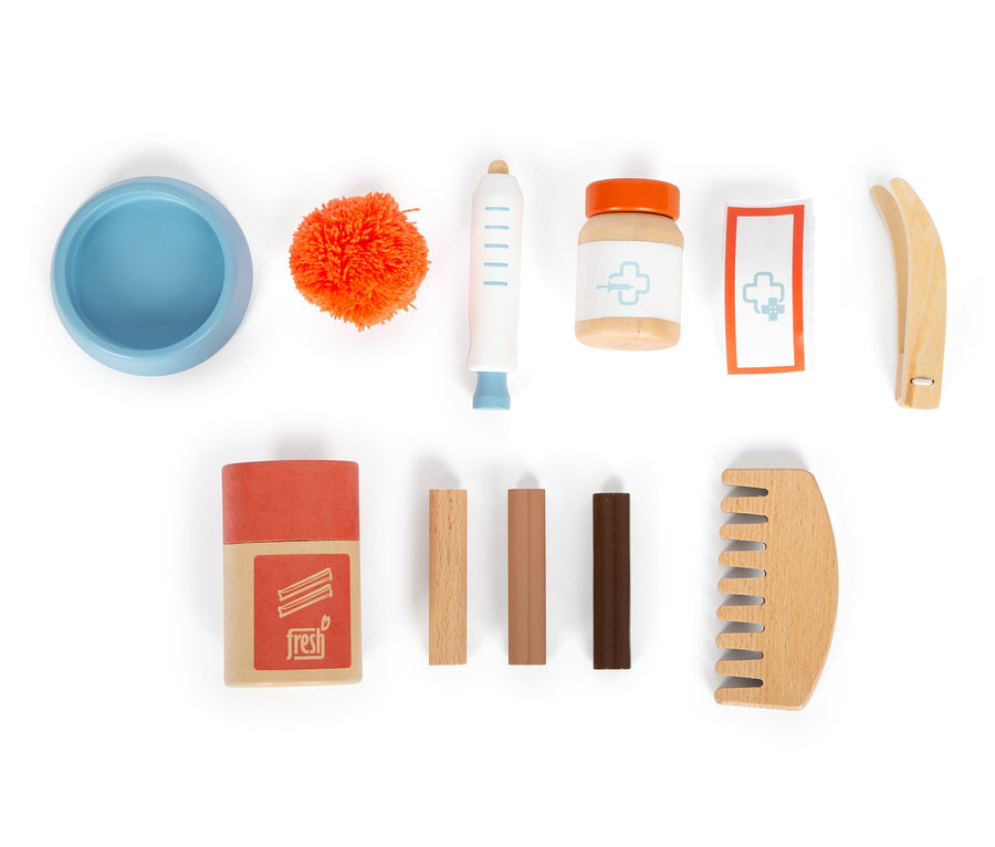 Eine leere blaue Schüssel, ein orangefarbener Bommel, eine Spritze, eine Medikamentenflasche, ein Verband, eine Pinzette, eine Schachtel, 3 Stäbchen und ein Kamm auf weißem Hintergrund.
