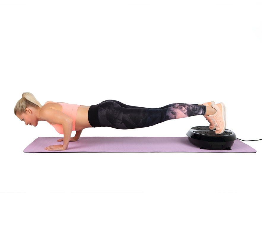 Blonde Frau macht Liegestütze auf einer lila Matte, ihre Füße auf einem VITALmaxx Vibrationstrainer.