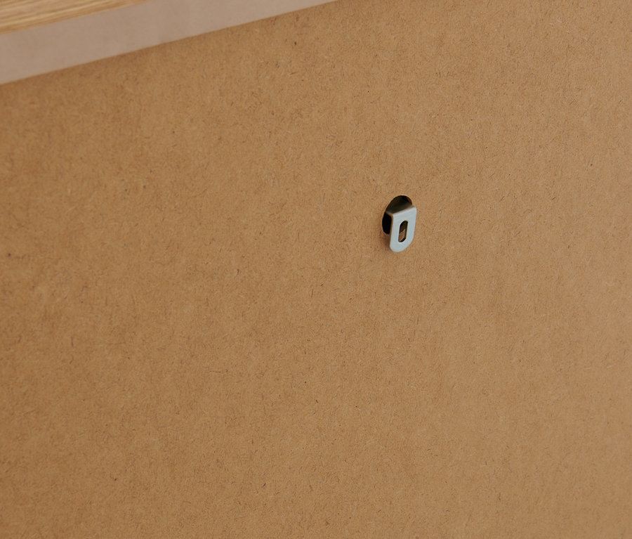 Detailaufnahme einer braunen Holzplatte mit silberfarbener Aufhängevorrichtung.