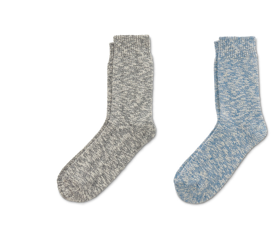 Zwei Paar Stricksocken liegen auf hellem Grund.