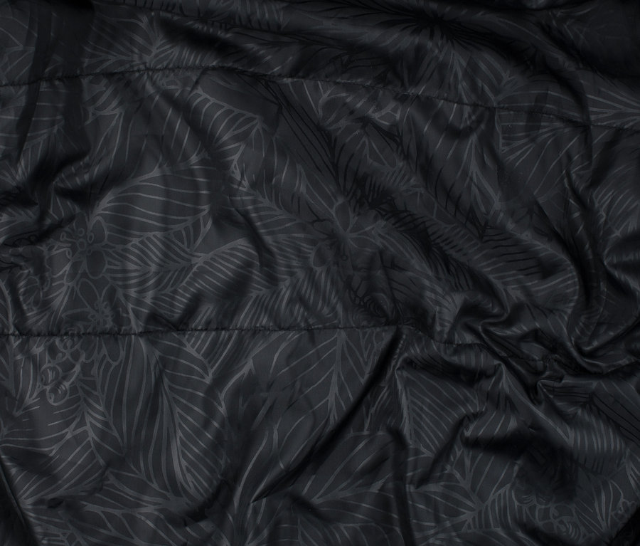 Detailansicht eines schwarzen Funktionsparkas mit Blattmuster.