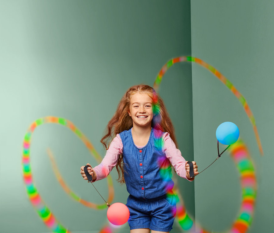 Mädchen jongliert mit 1 Paar LED-Pois in einem grünen Studio.