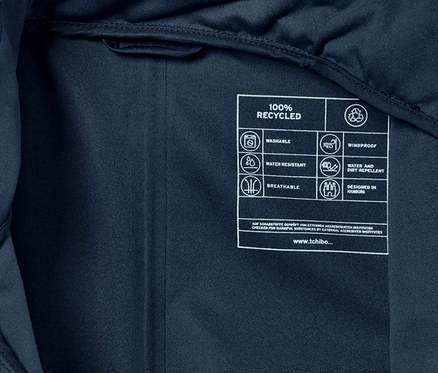 Detailaufnahme des Innenetiketts eines Regen-Einteilers, das Symbole und Text zu Recycling, Wasserbeständigkeit und Atmungsaktivität zeigt.