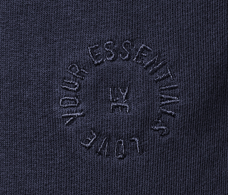 Detailaufnahme einer dunkelblauen Sweatpants mit dem Schriftzug "YOUR ESSENTIALS LY LOVE" im Kreis.