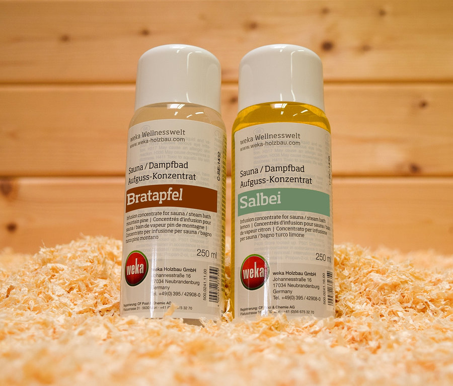 Zwei Flaschen WEKA-Geschenkset »Dufterlebnis« stehen nebeneinander auf einem Untergrund aus Holzspänen vor einem Holzhintergrund.