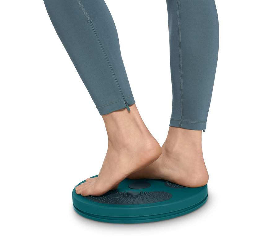 Füße einer Frau in Leggings stehen auf einer Twister-Scheibe.