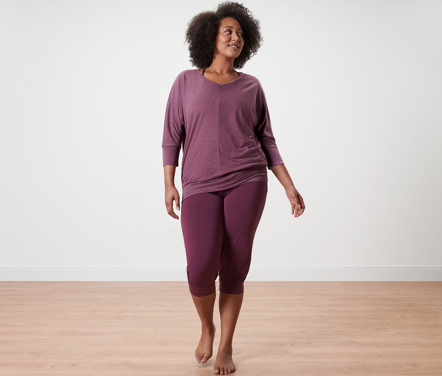 Frau geht, trägt eine mauvefarbene 3/4-Yogahose und ein mauvefarbenes Yogashirt.