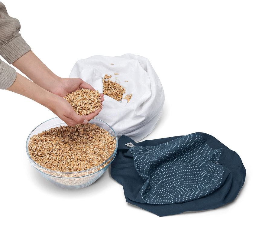 Person befüllt Meditationskissen mit Getreide aus einer Schüssel.