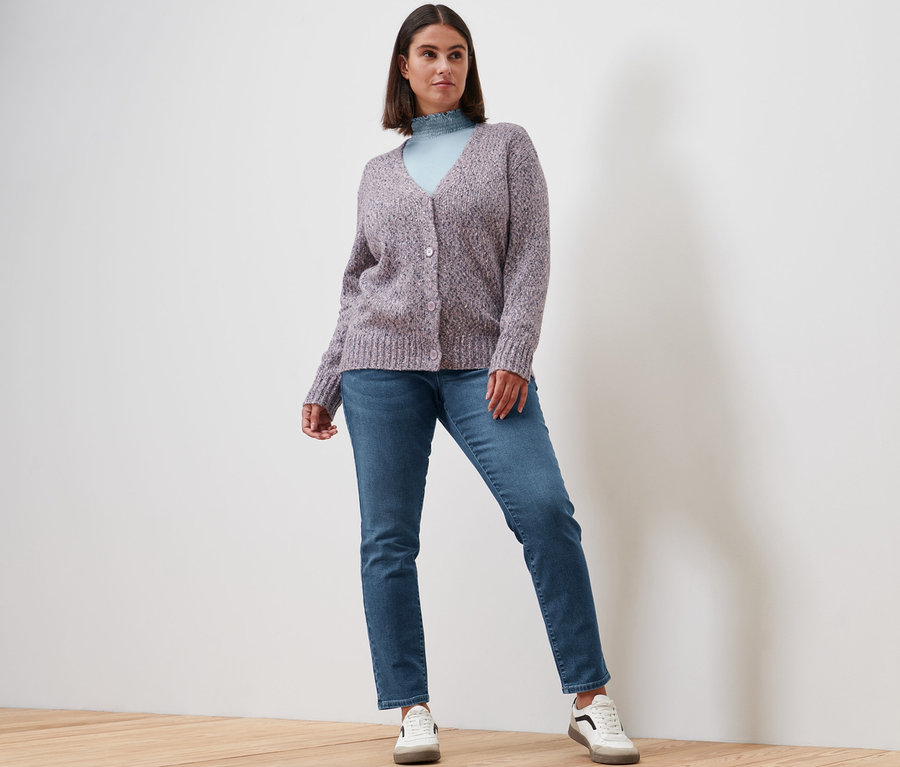 Frau posiert in Blusenshirt mit Stehkragen, rauchblau, Slim-Denim »Fit Emma«, midblue denim, Strickjacke mit Wolle und Leder-Sneaker.