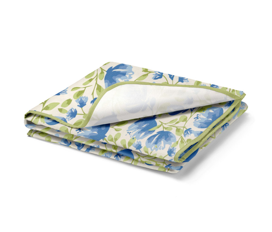 Gefaltete kleine Picknickdecke mit blauem Blumenmuster und grünem Rand.