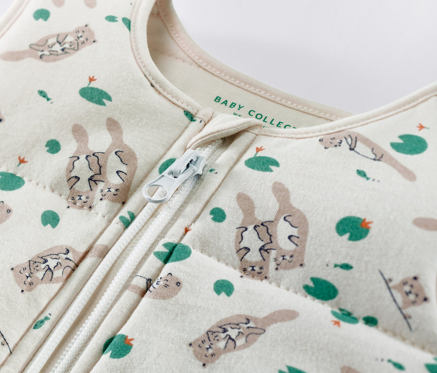 Detailaufnahme eines Baumwollschlafsacks mit Otter- und Seerosenmuster und Reißverschluss in der Mitte.