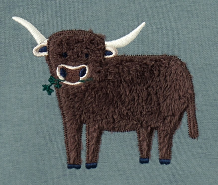 Kleinkind-Sweater mit aufgenähtem, zotteligem, braunem Rind mit weissen Hörnern, das eine grüne Pflanze im Maul hält, auf blaugrünem Hintergrund.