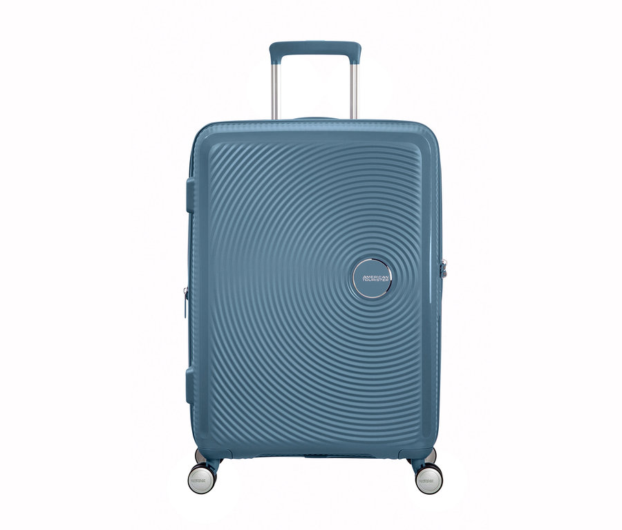 Ein mittelgroßer, blauer American Tourister Hartschalenkoffer »Soundbox« Spinner steht vor einem weißen Hintergrund.
