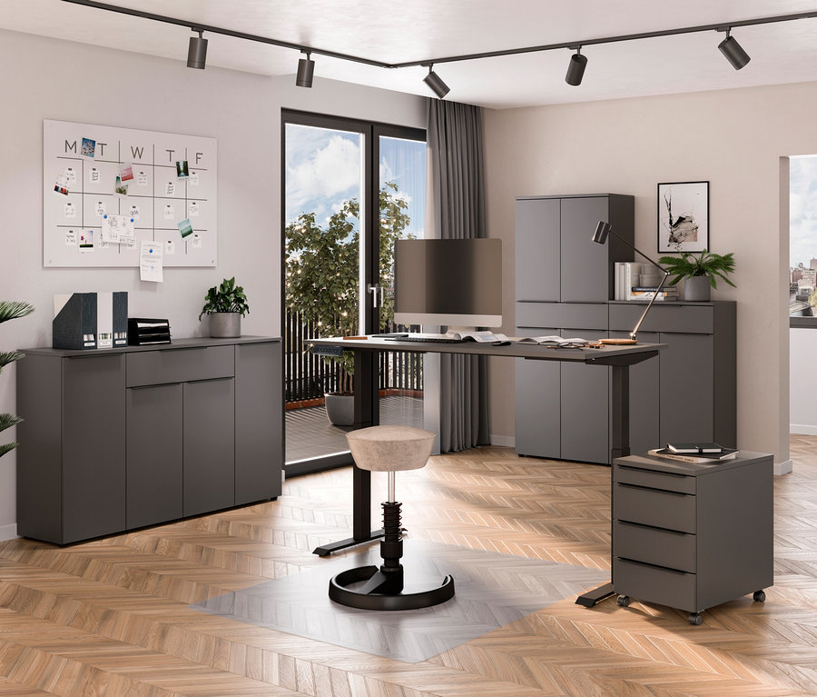 Ein modernes Arbeitszimmer mit einem elektrisch höhenverstellbaren Schreibtisch »Kopenhagen« in Graphit, einem Drehstuhl und Aufbewahrungsmöbeln.