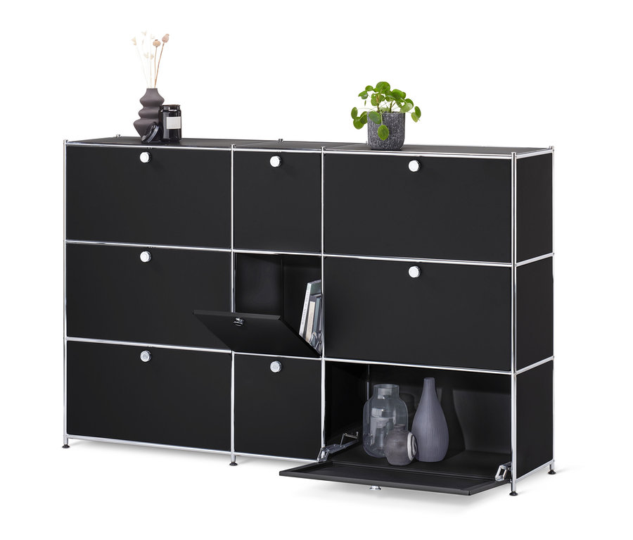 Schwarze Kommode »CN3« mit 9 Klappen, von denen eine Bücher und zwei Vasen zeigen.