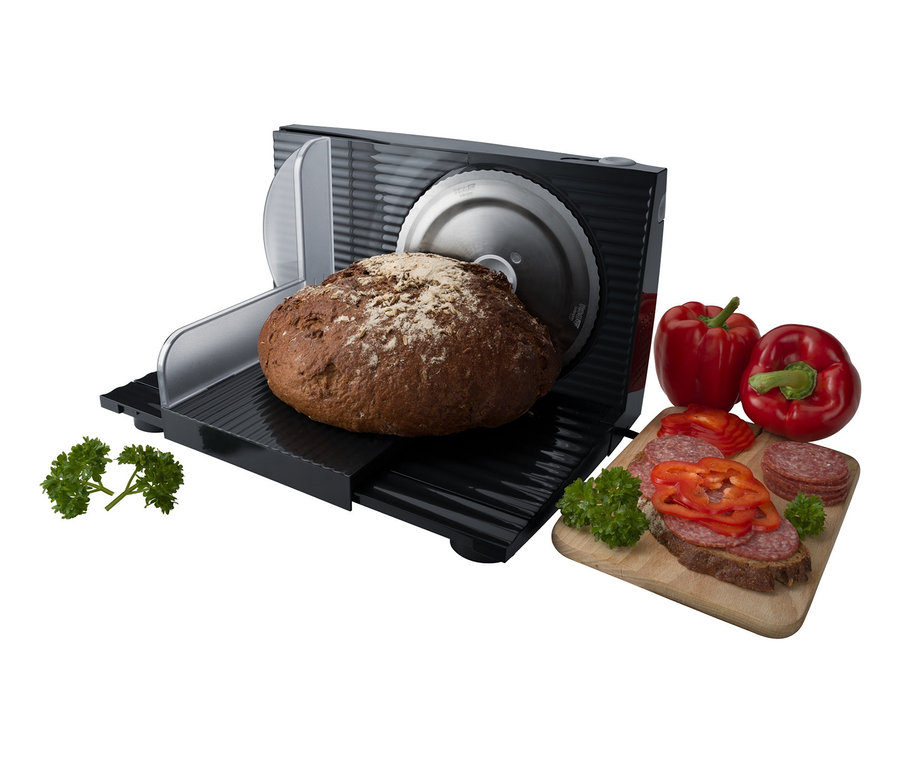 Ein braunes Brot wird auf der Steba Elektrischer Allesschneider »AS 100« neben Paprika und Wurstbrot geschnitten.